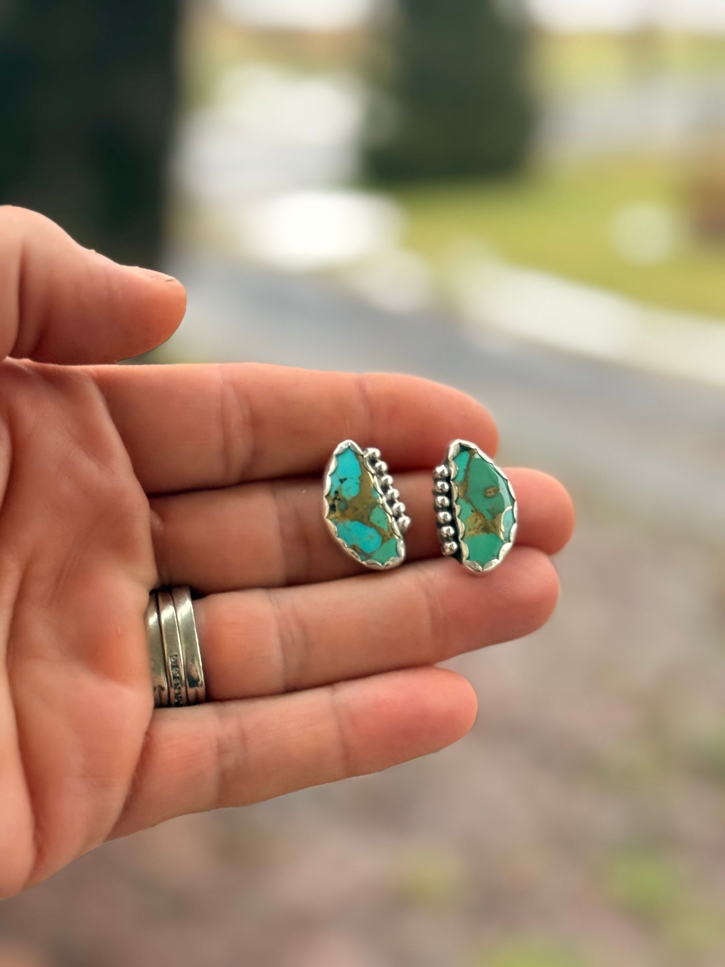 Red Pony Brand sterling silver and mohave turquoise stone earrings with an outside blurry background