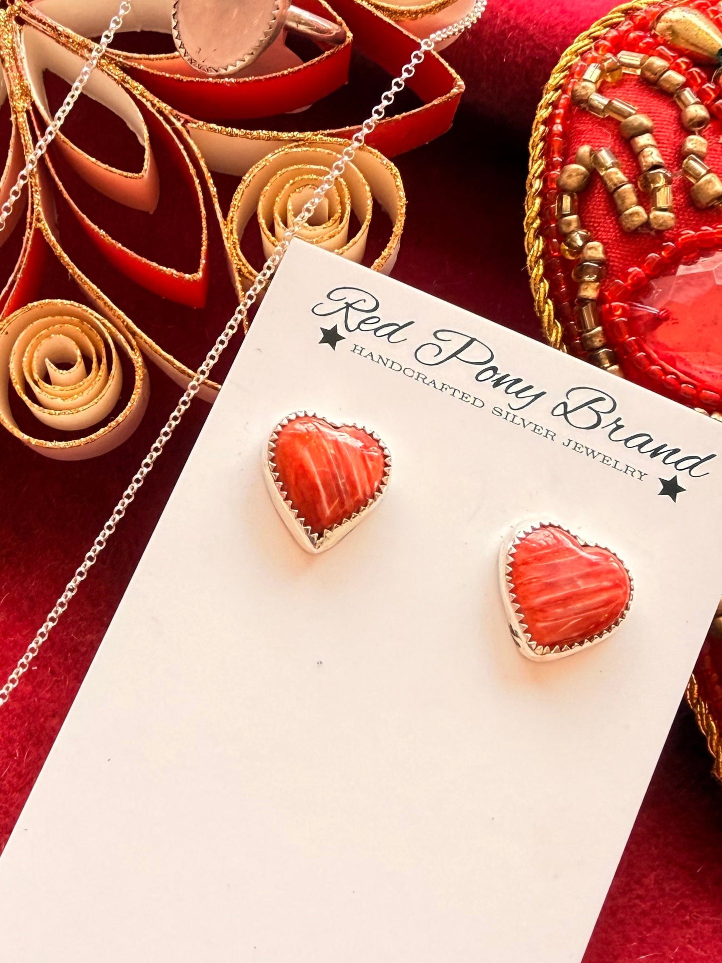 Red Pony Brand pink spiny oyster heart earrings on red fancy background